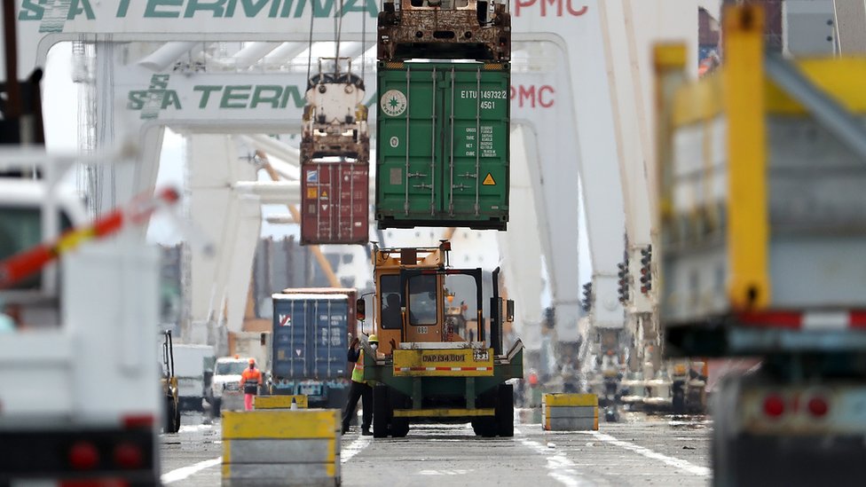 A shipping container is offloaded in a port in California