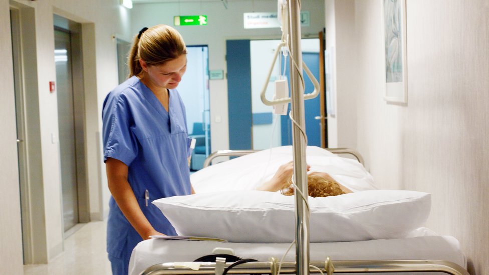 Медсестра разговаривает с пациентом на больничной койке