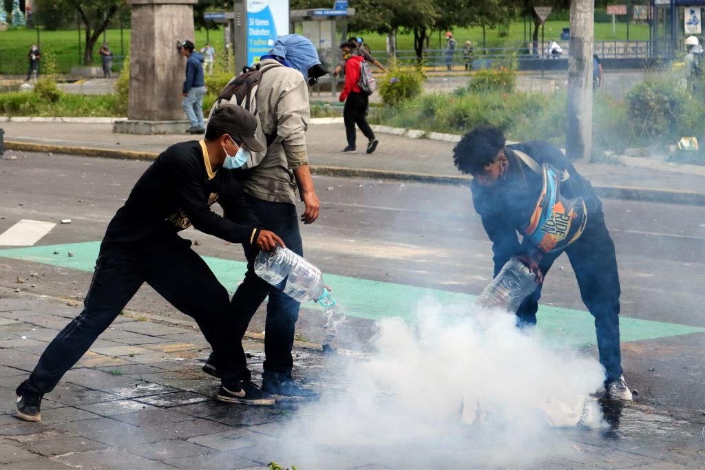 Manifestantes intentan apagar una munición de gas lacrimógeno en las protestas que se desarrollan en Quito, Ecuador.