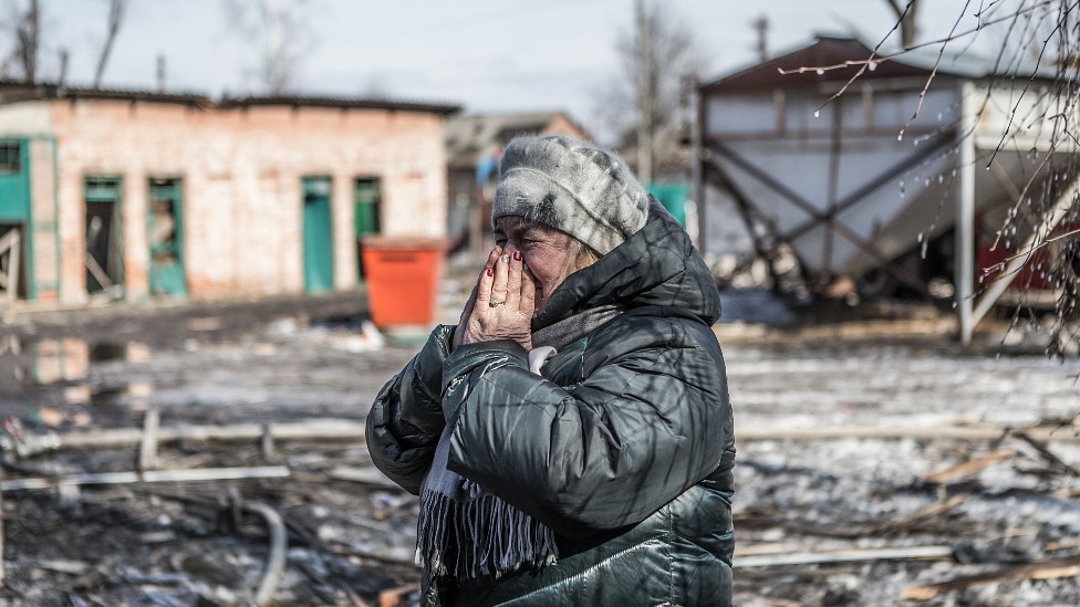 Una mujer se toma el rostro llorando entre edificios devastados por los bombardeos en Járkiv