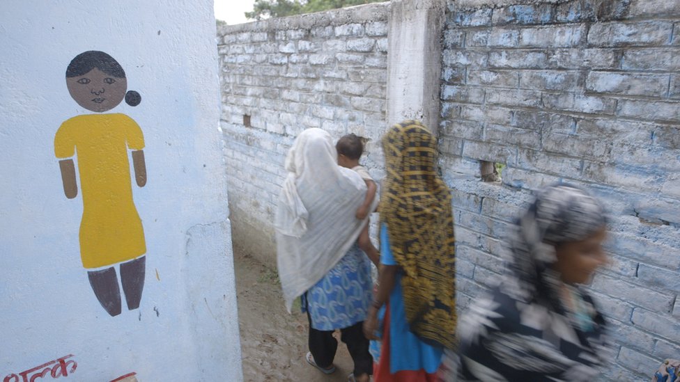 Женщины проходят мимо вывески в здание Шри-Ланки