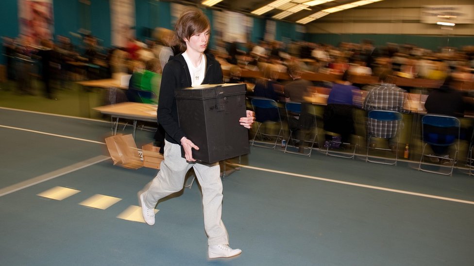 Подросток бежит с урнами для голосования