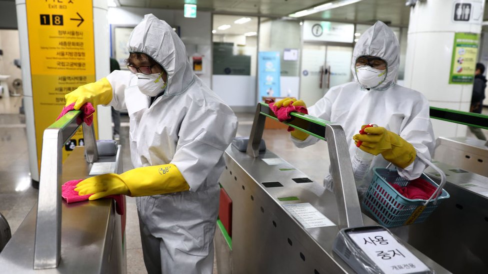 Funcionários usando equipamento de proteção desinfectam estação de metrô em Seul