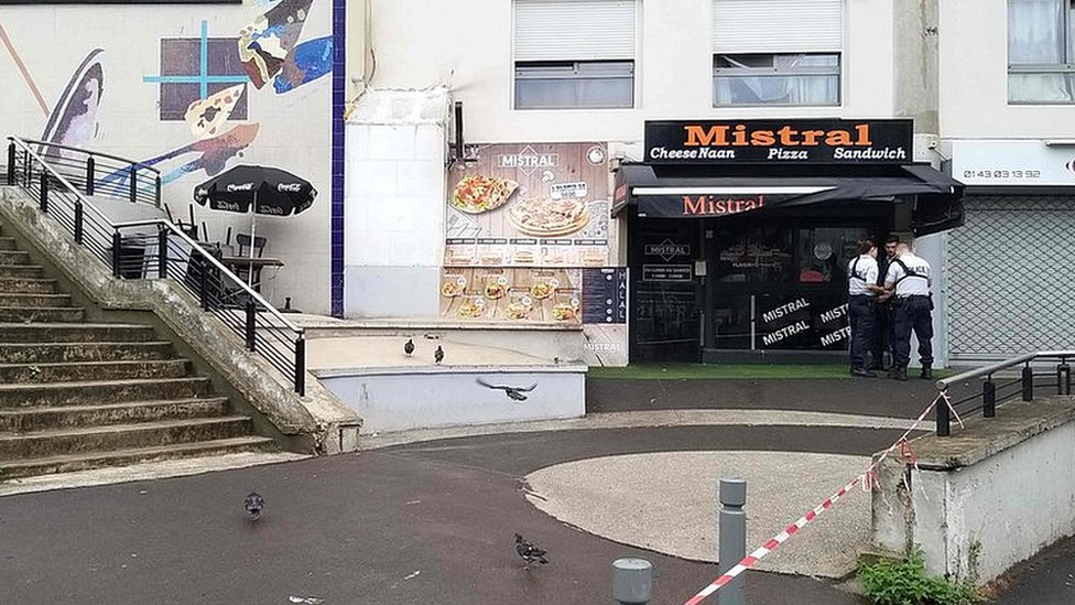 Police stand in front of the shop where a waiter was shot dead by a customer allegedly angry at having to wait for a sandwich, in the eastern Paris suburb of Noisy-le-Grand on August 17, 2019