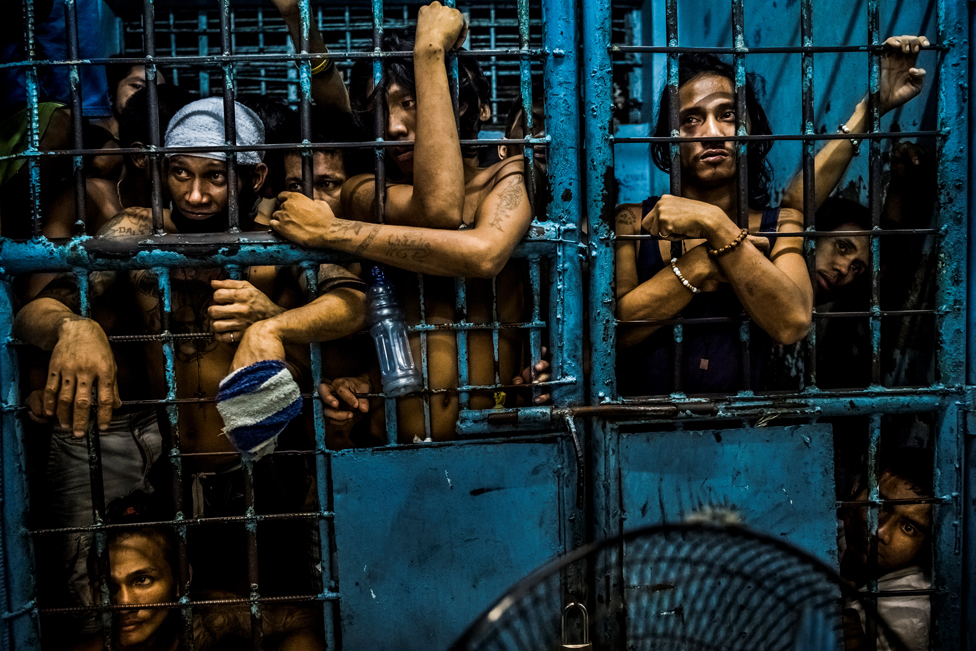 Заключенные наблюдают, как подозреваемые в употреблении наркотиков обрабатываются в полицейском участке в Маниле, Филиппины