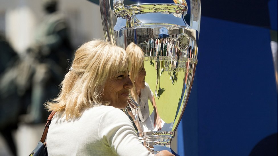 Женщина позирует с трофеем Лиги чемпионов УЕФА на площади Пласа-де-Ориенте в Мадриде