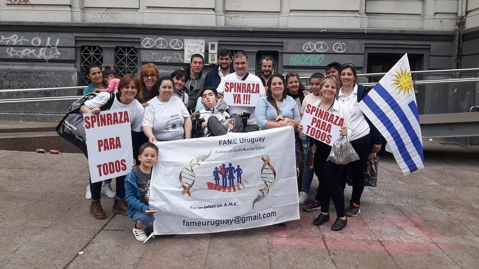 Marcha en Uruguay de familiares de pacientes de AME con carteles que dicen "Spinraza para todos" y "Spinraza ya"