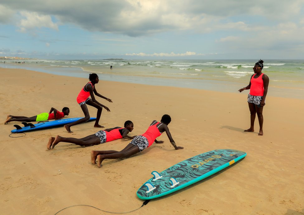 Khadjou Sambe teaches girls and women surfing techniques on the beach