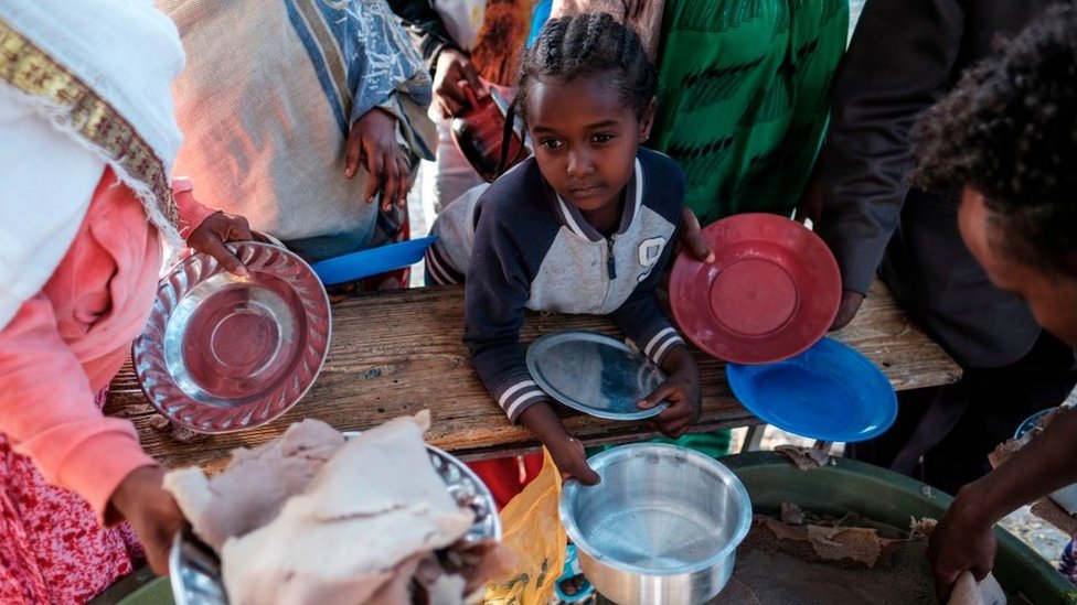 A displaced child from Western Tigray waits at meal time to receive a plate of food outside a classroom in the school where they are sheltering in Tigray's capital Mekele on February 24, 2021.