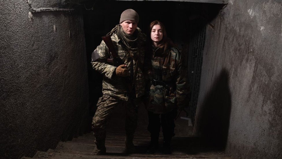 Svyatoslav Fursin and Yaryna Arieva in military uniforms holding weapons