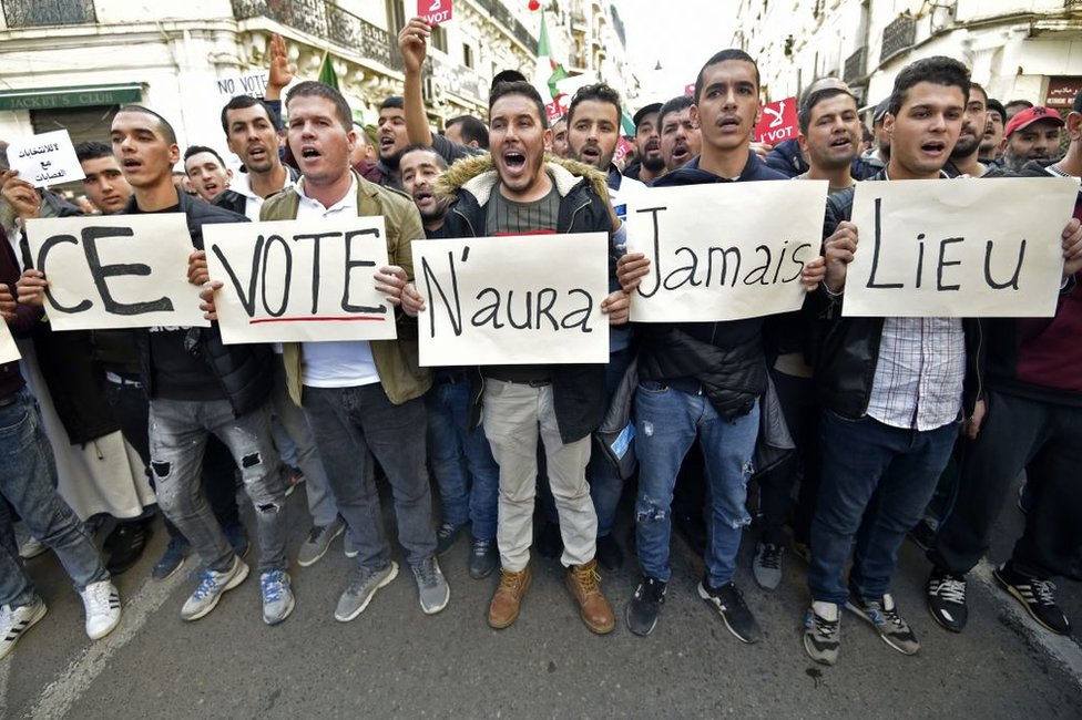 6 декабря алжирские демонстранты несут плакаты с надписью на французском: «Такого голосования никогда не будет».