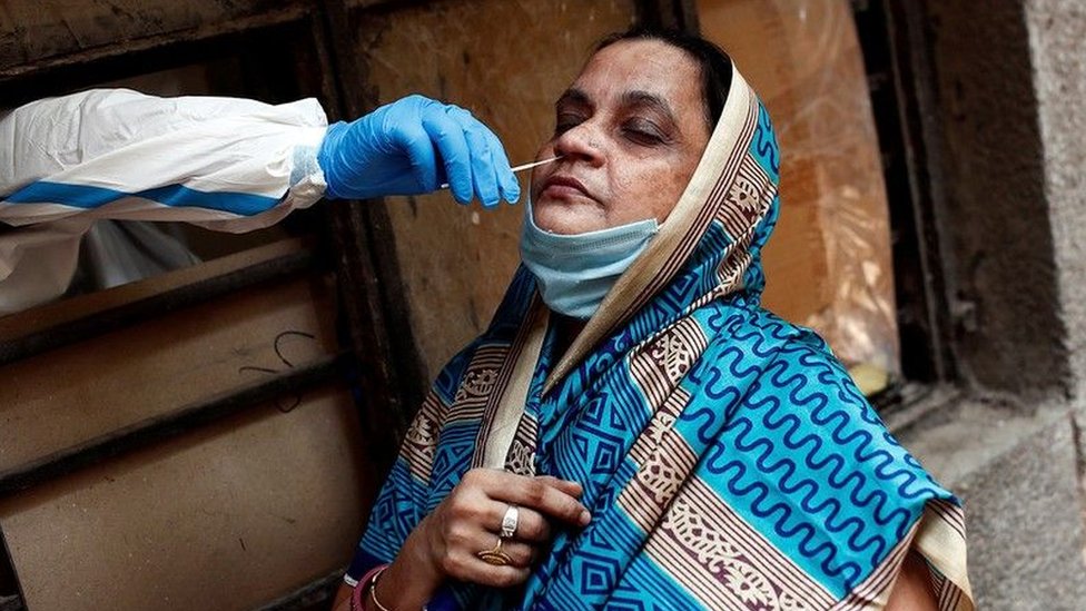 A woman wearing a headscarf undergoes a nose swab to detect Covid-19