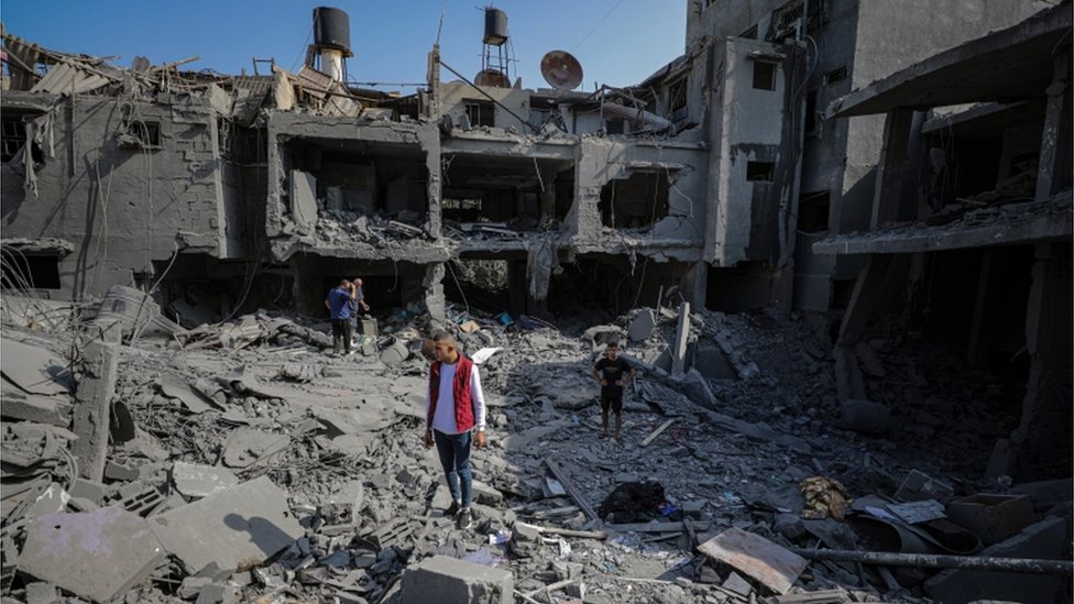 Warga Gaza mencari tanda-tanda penyintas di balik reruntuhan gedung.