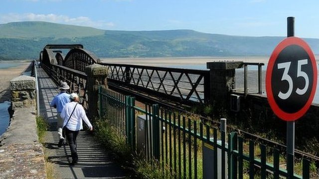 Walkers crossing the Barmouth bridge across the Mawddach estuary, Gwynedd