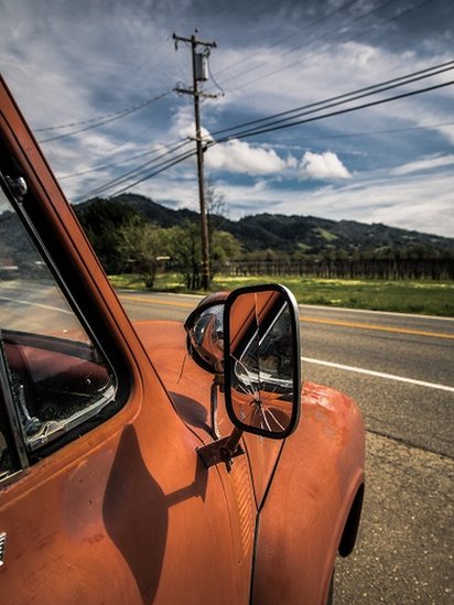 Espejo de retrovisor roto en un carro viejo color naranja.