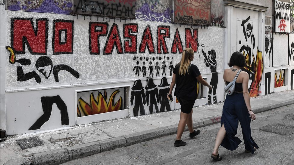 Женщины проходят мимо лозунга «Они не пройдут», который был нанесен баллончиком на стены Экзархии.