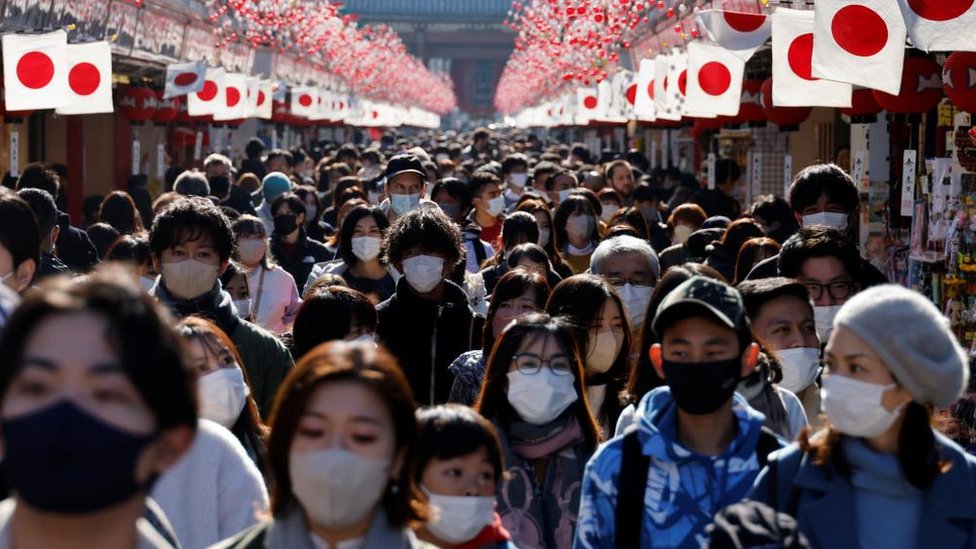 Visitantes con mascarillas protectoras caminan bajo las decoraciones para el Año Nuevo en la calle Nakamise que conduce al templo Senso-ji en el distrito de Asakusa, un lugar turístico popular, en medio de la pandemia de covid-19 en Tokio, Japón