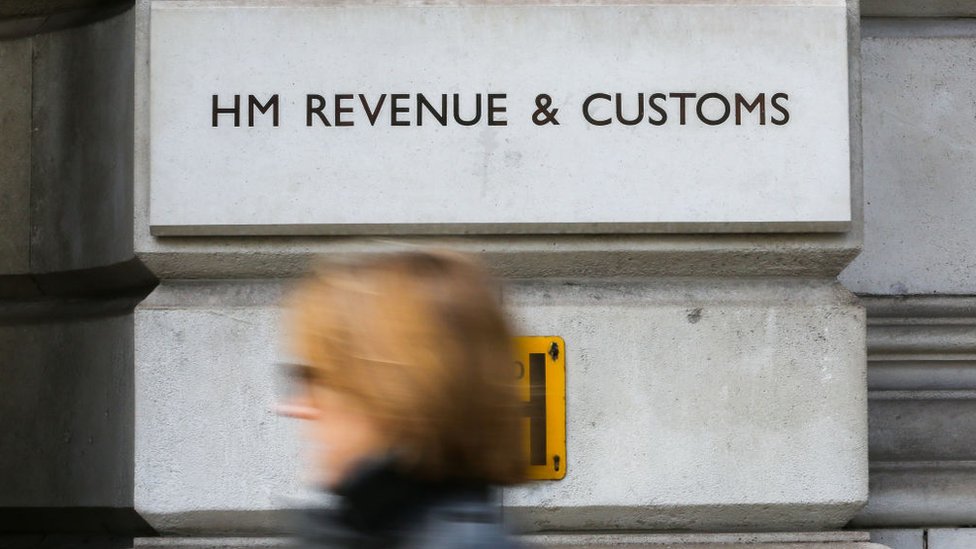 Женщина проходит мимо здания HM Revenue and Customs