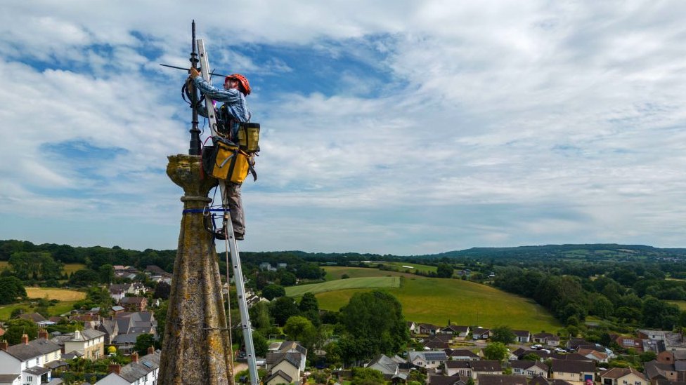 Worker fixing the lightning rod at the top of a church tower