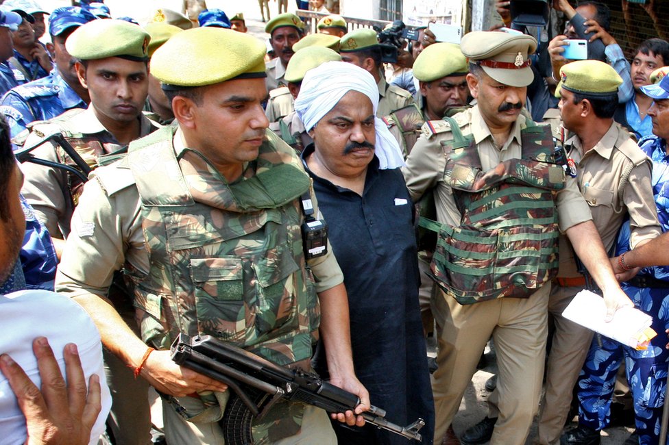 Agentes de policía escoltan a Atiq Ahmed, ex legislador del Parlamento indio, acusado en varias causas penales, a las puertas de un tribunal en Prayagraj, India, 13 de abril de 2023.