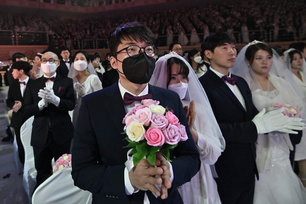 زوجان يرتديان قناعان واقيان يشاركان في حفل زفاف جماعي نظمته كنيسة التوحيد في غابيونغ