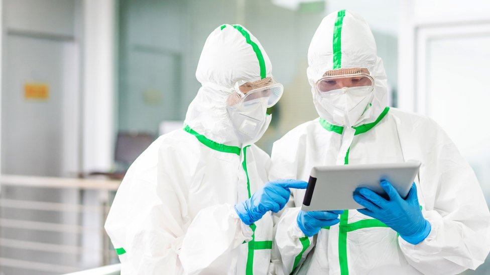 Dos médicos protegidos analizan resultados en una tableta.