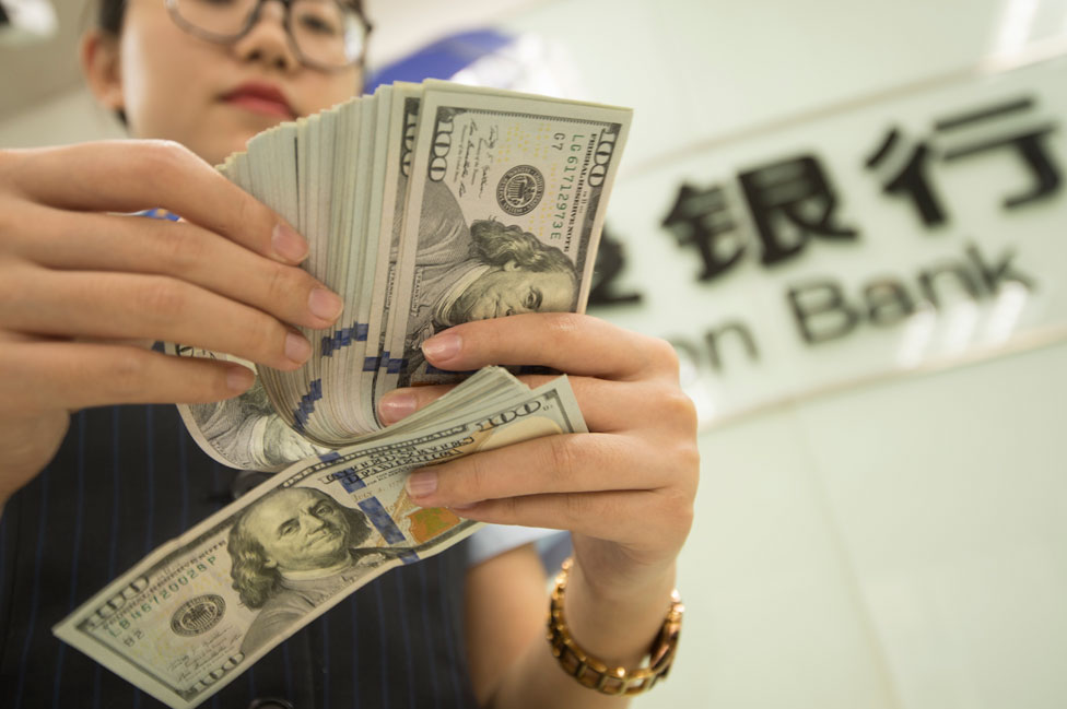 Una cajera de un banco chino contando dólares