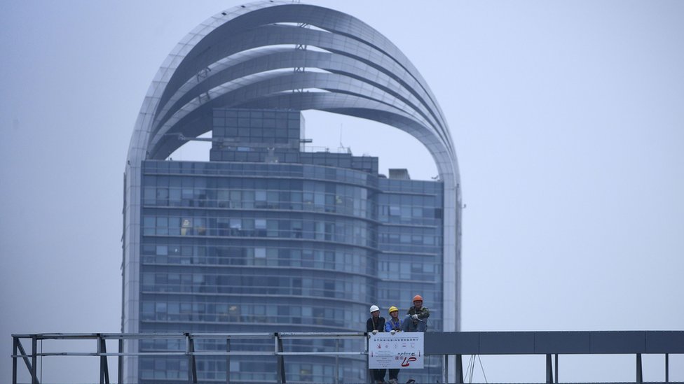 Группа рабочих смотрит с крыши здания в Шанхае