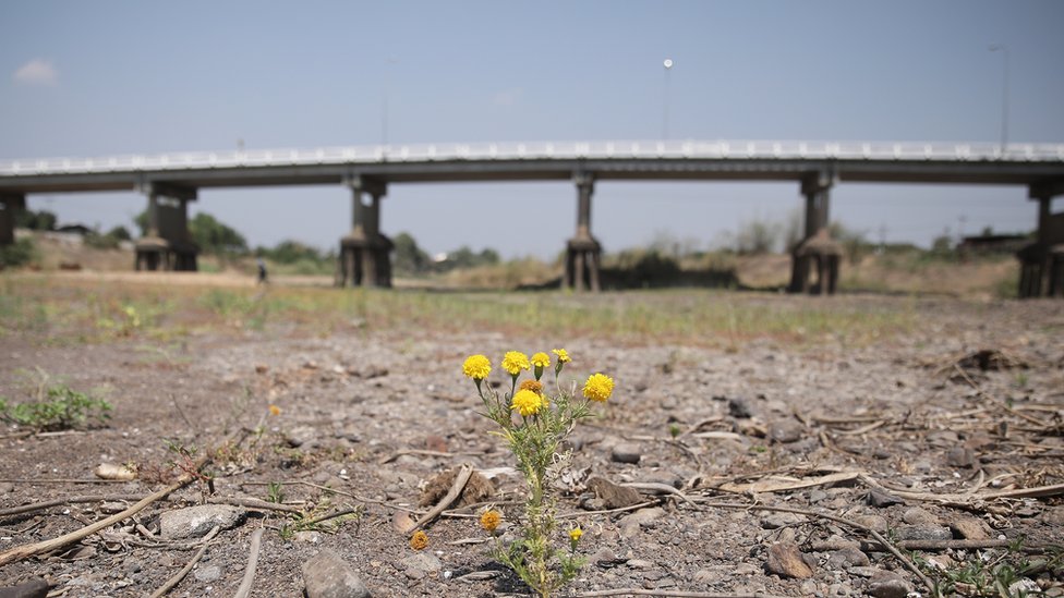 Imagem de terra seca, com uma ponte atrás