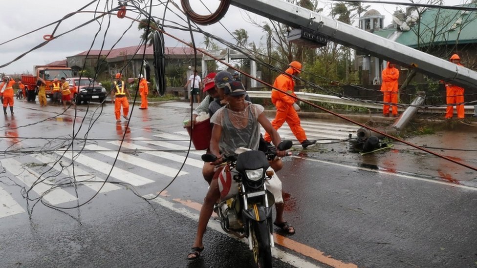 Filipino villagers move past a toppled electric post in the typhoon-hit town of Tigaon, Camarines Sur, Philippines, 01 November 2020