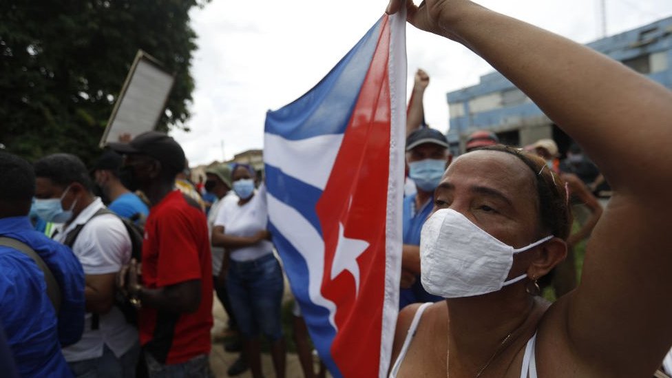 Mujer protestando con bandera cubana.