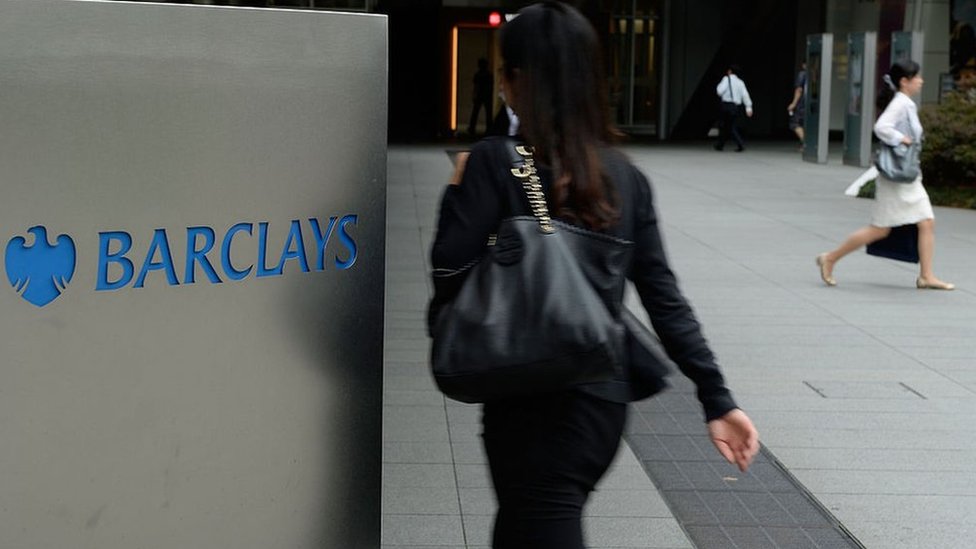 Люди, идущие мимо вывески Barclays