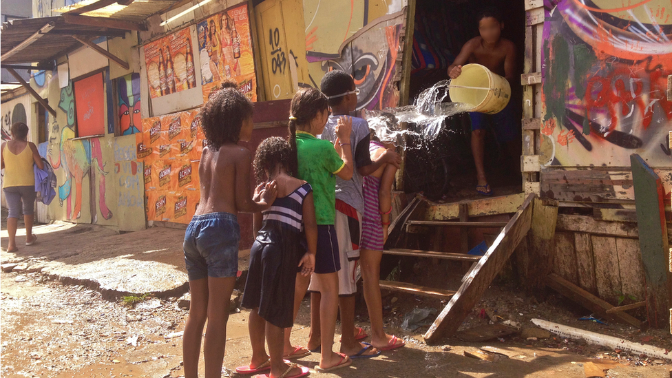 Crianças brincando com balde de água na Favela do Moinho, em São Paulo