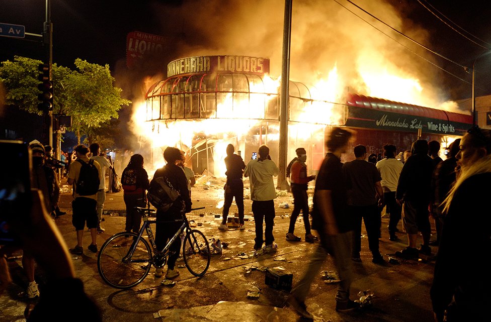 Protesters gather to watch a liquor store burning
