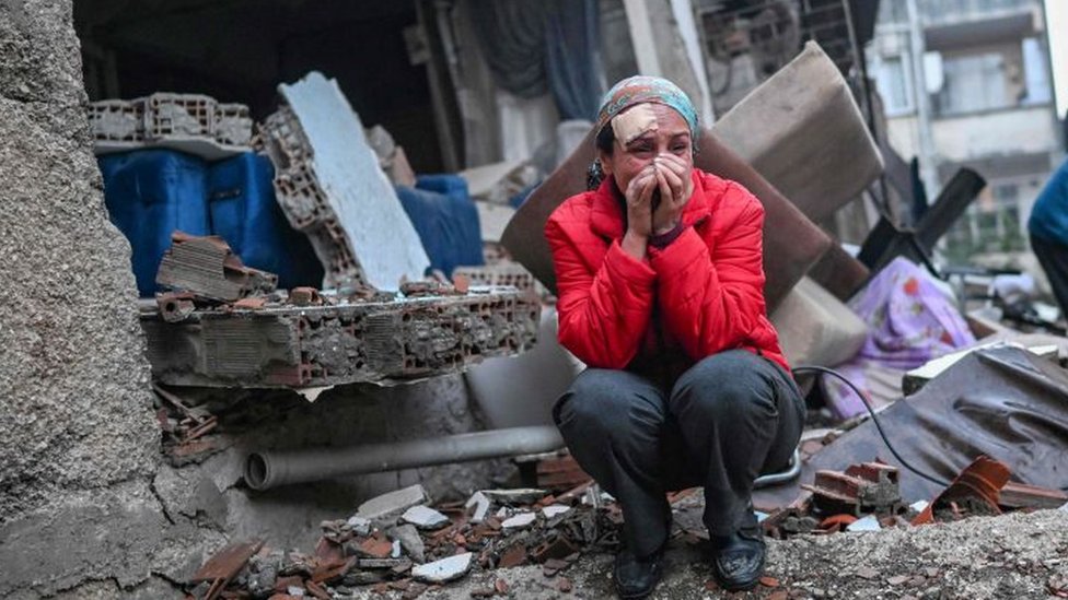 Una mujer sentada en los escombros de un edificio destruido por el terremoto en la ciudad de Hatay