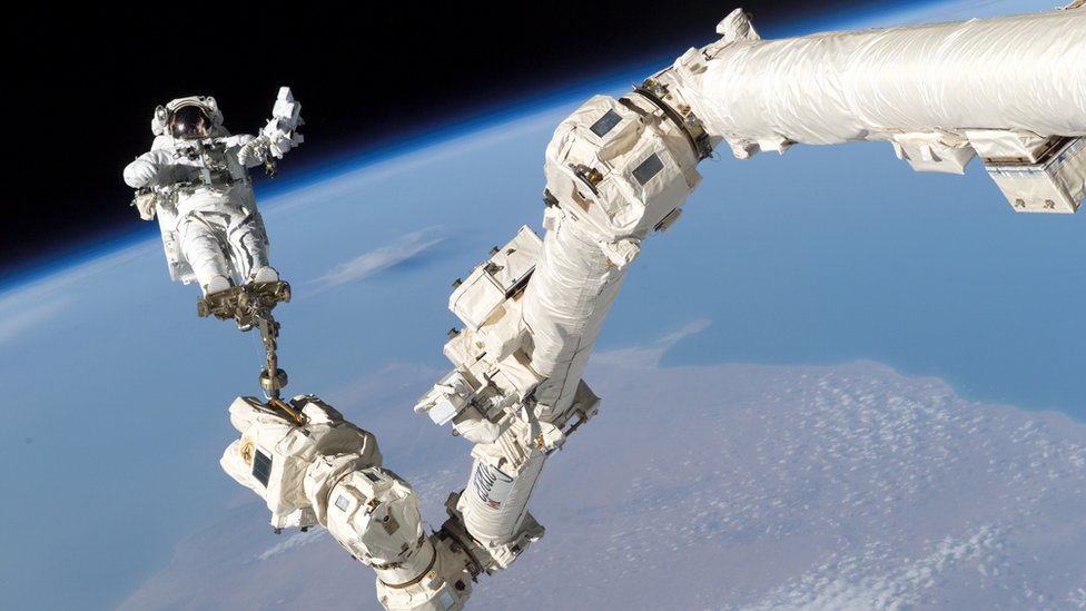 Астронавт Стивен К. Робинсо привязан к стопе на Международной космической станции Canadarm2