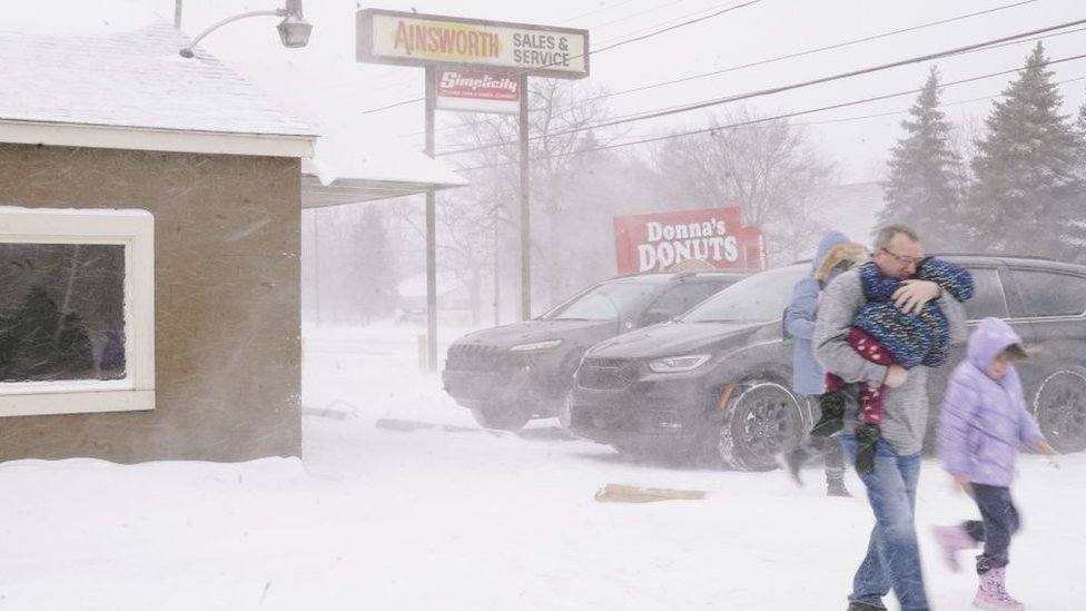 A family huddled together, moves quickly to their car, to get out of the frigid cold from a massive winter storm affecting most of the USA., in Flint, MI on December 23, 2022
