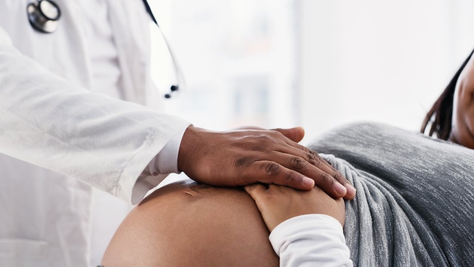 médico com mão em cima de barriga de mulher grávida