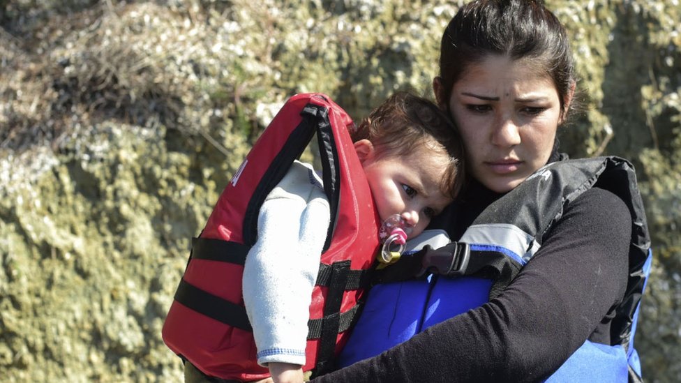 Syrian migrant women hold babies wearing life-jackets before boarding a dinghy to cross the Aegean Sea to the Greek island of Lesbos from the Ayvacik coast in Canakkale on 28 February 2016.