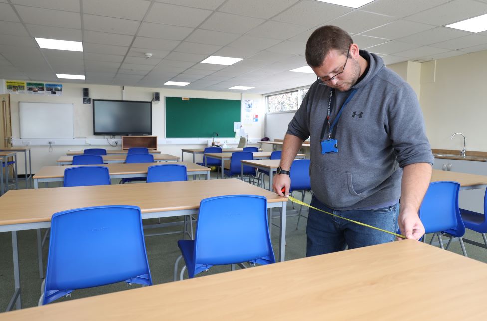 26 августа 2020 г., среда. Измерения пропусков между столами производятся в классе, поскольку идет подготовка к новому учебному семестру в школе Олдервуд в Олдершоте, графство Хэмпшир.