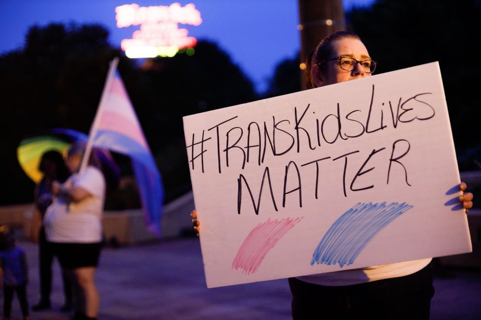 Una defensora de los derechos de las personas transgénero sostiene un cartel afuera del Capitolio de Ohio durante la manifestación en junio de 2021 contra una enmienda a un proyecto de ley que prohibiría a las mujeres transgénero participar en deportes femeninos en escuelas secundarias y universidades.