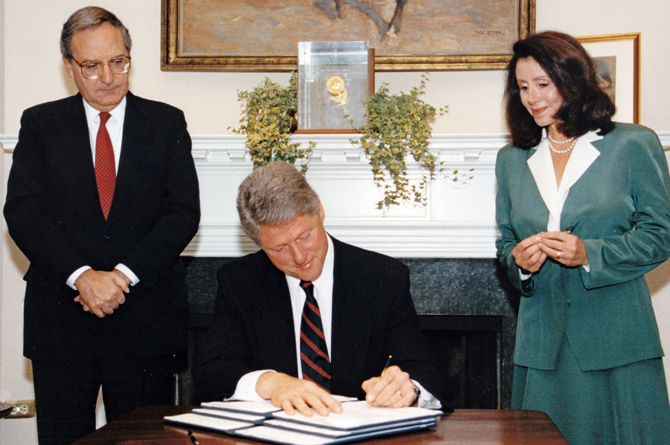US Senate Majority Leader George Mitchell (left) and US Representative Nancy Pelosi watch as President Clinton (centre) signs an executive order