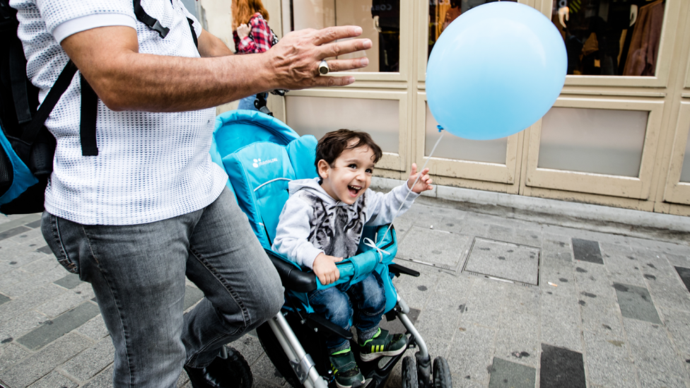 Niño en un carrito de bebé en la calle con un globo