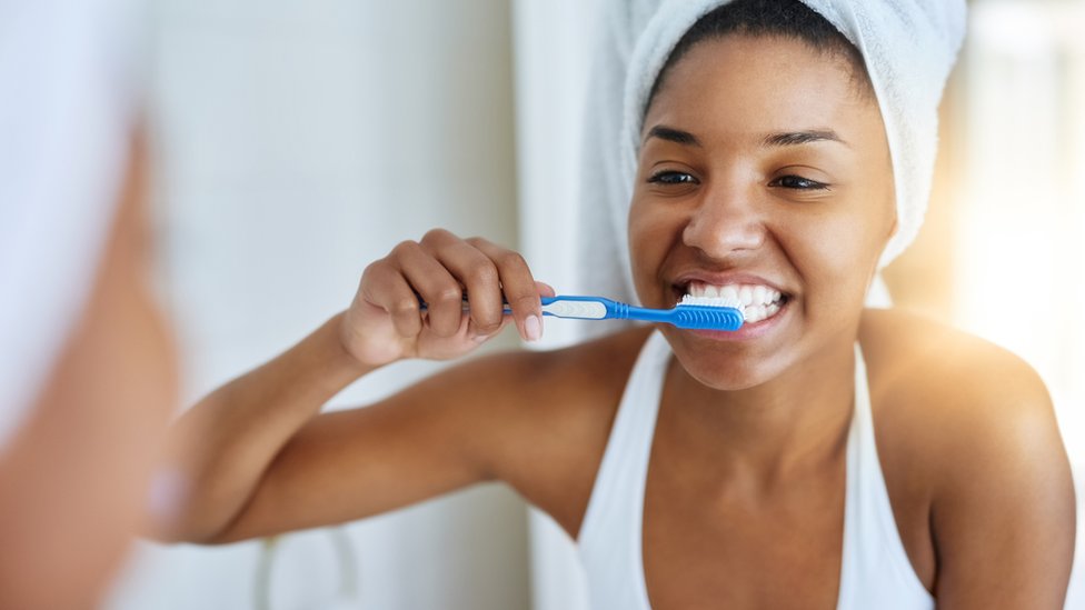 Una joven lavándose los dientes.