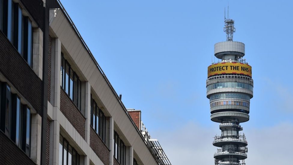 Лондонская башня BT возвышается над зданиями вокруг нее, по ее окружности разбросаны спутниковые антенны и оборудование связи