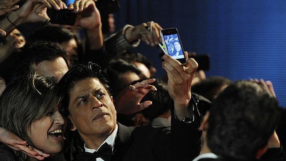 Aktor Shah Rukh Khan berpose dengan penggemar.