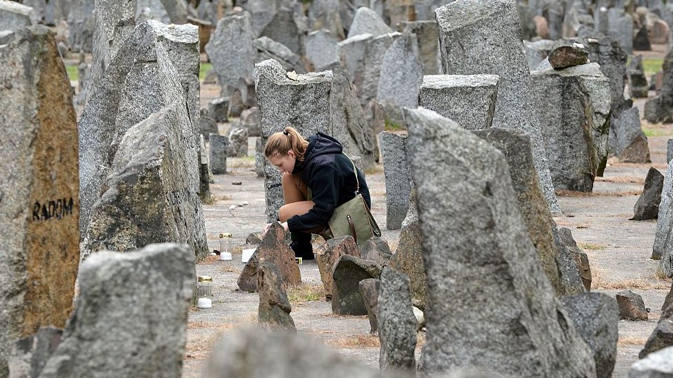 A Polish girl scout lights a candle in front of the monument of Treblinka World War II-era Nazi death camp on October 2, 2013 in Treblinka