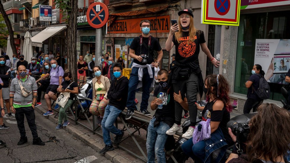 A woman speaks to other protesters wearing protective masks during a demonstration, in the Vallecas area