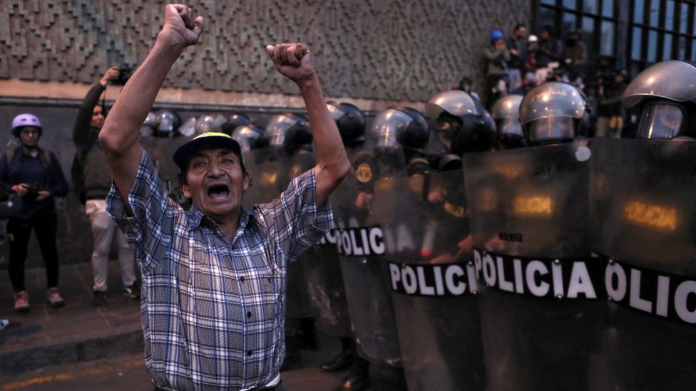 Un hombre protesta contra el gobierno frente a agentes de la policía en Lima, Perú.