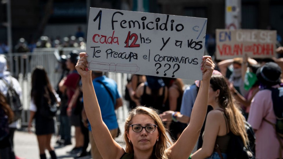 Mujer sosteniendo cartel en protesta en Santiago